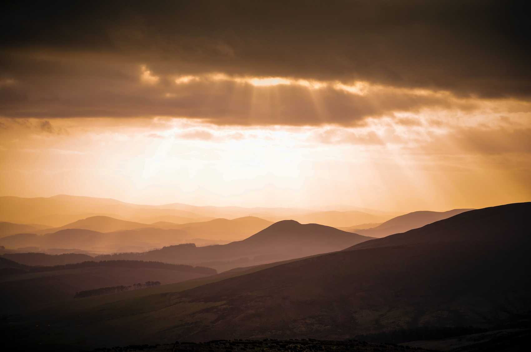 Sun rays shining through clouds over a mountain range