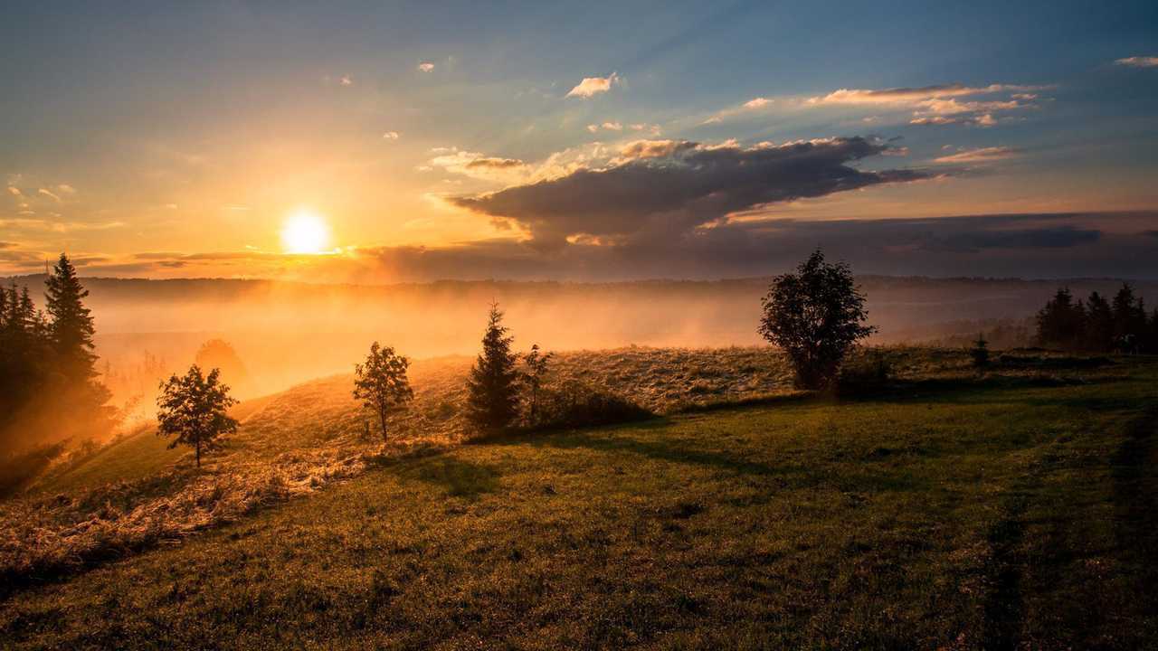 A sunrise over a distant, misty hill